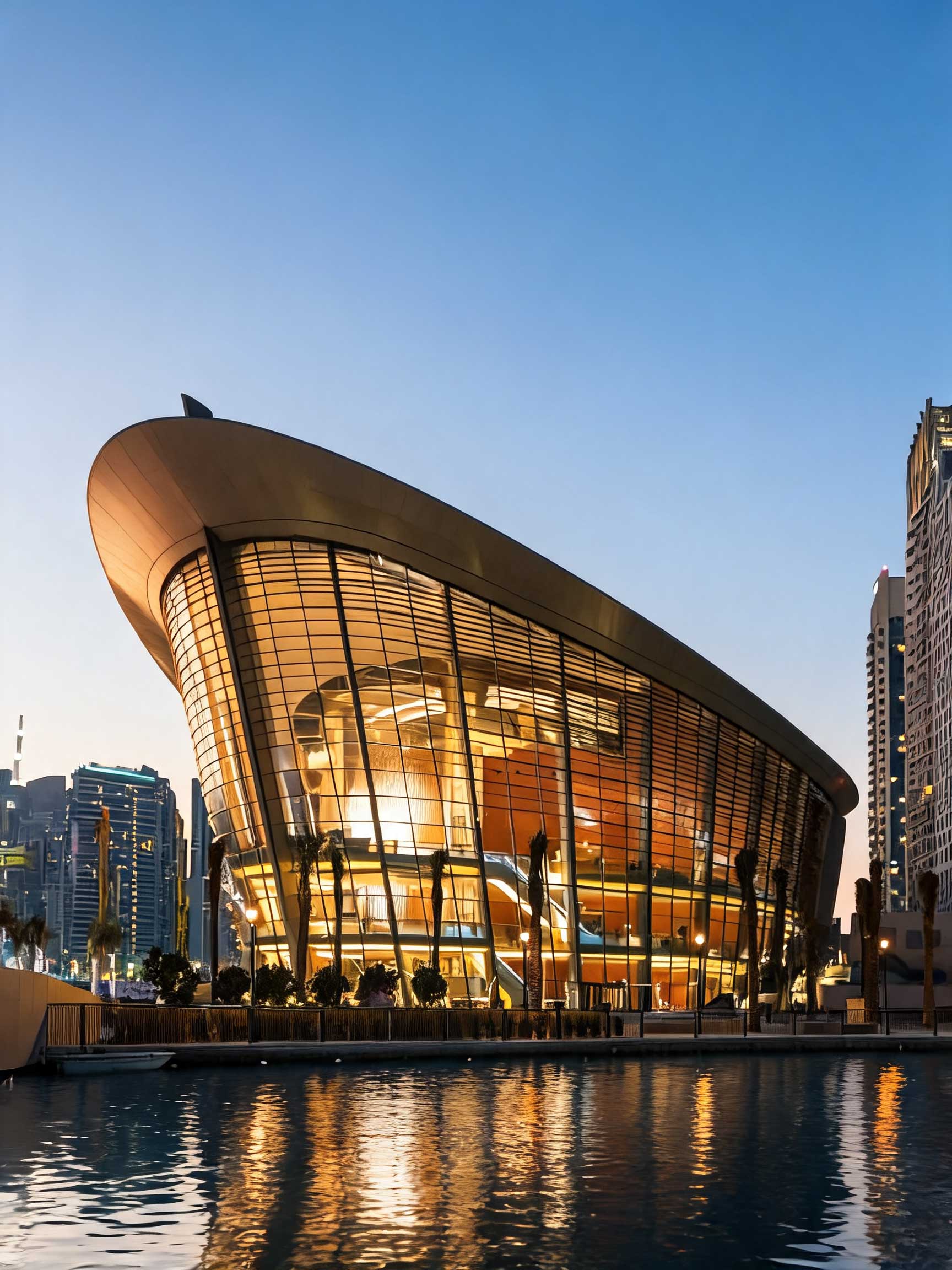 Dubai Opera lit at dusk, reflected in the water