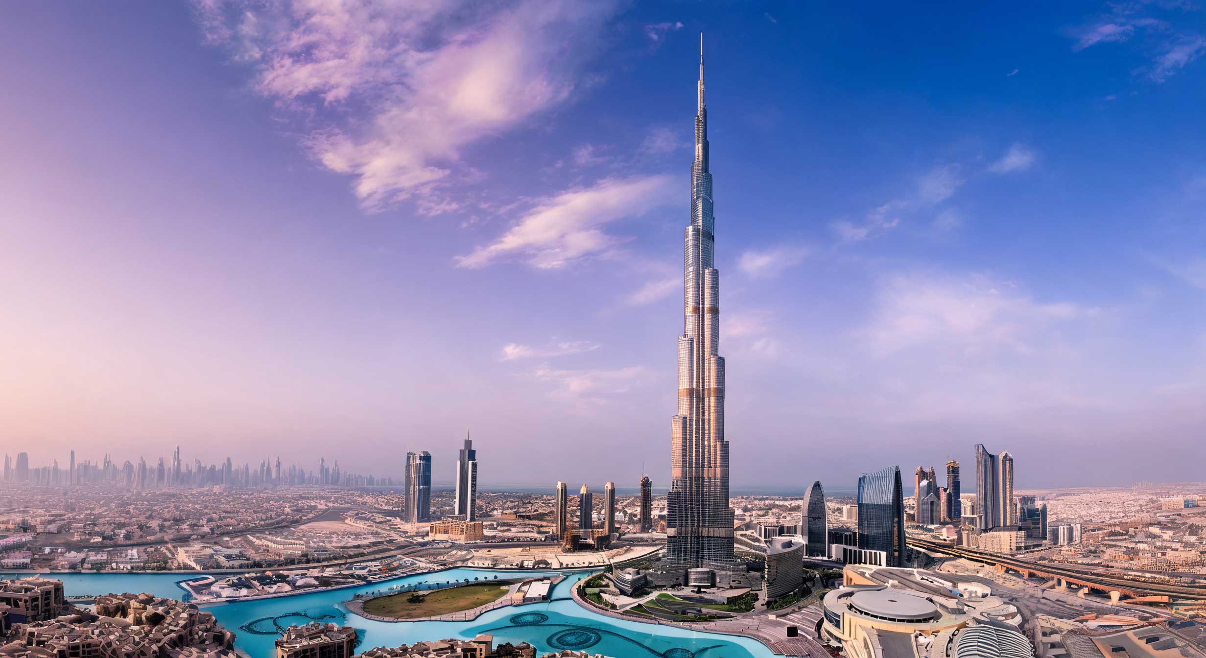 The Burj Khalifa rising over Downtown Dubai and the Dubai Fountain lake under a lilac and blue sky